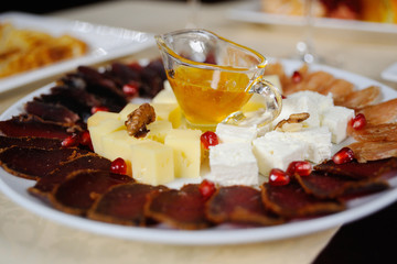 honey in a cup among slicing cheese and sausages