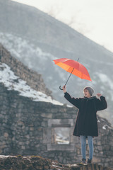 Young woman standing at the hill holding umbrella