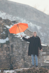 Young woman standing at the hill holding umbrella