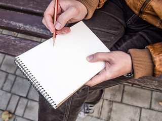 Close up of man's hands with pencil writing on notebook mockup
