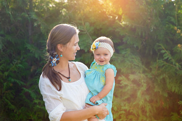 Mom keeps daughter in her arms and plays on the nature