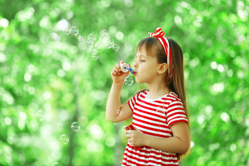 Little girl playing with bubbles in the park