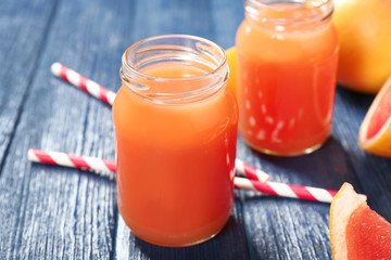 Fototapeta na wymiar Grapefruit juice in bottles and fresh fruits on dark blue wooden background