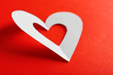 Cut out white paper heart on red background