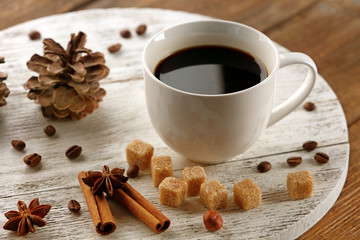 Cup of coffee with sugar and cinnamon on white wooden mat