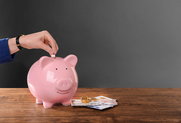 Woman putting coin in pig moneybox
