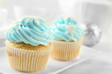 Two tasty blue cupcakes with decorations on light background