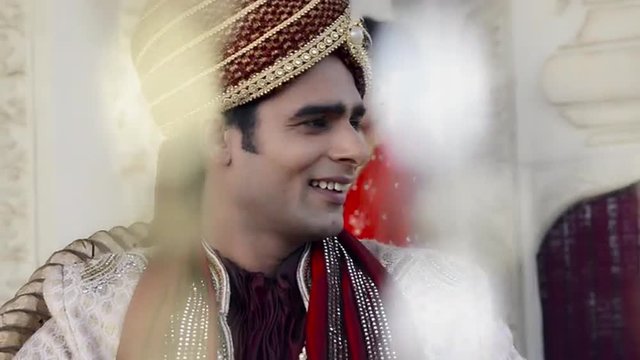 Shot of a Indian groom with bride standing in the background