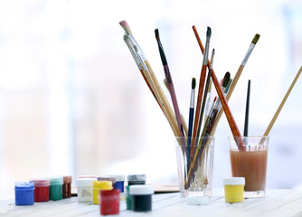 Drawing set with brushes and paints on white table
