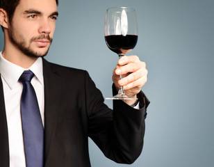 Man looking at the glass of red wine on blue background