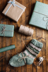 Pair of knitted socks with wrapped gifts for Christmas on wooden table