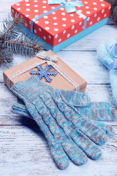 Composition of warm socks and gloves with Christmas gifts on white wooden background, close up