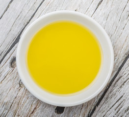 Olive oil in white bowl over wooden background