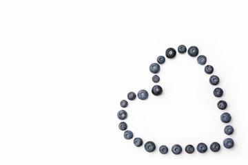 Blueberries hollow heart in a corner on white background directly from above