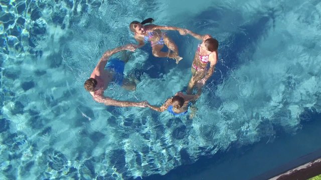 Aerial view of family in swimming pool making circle together