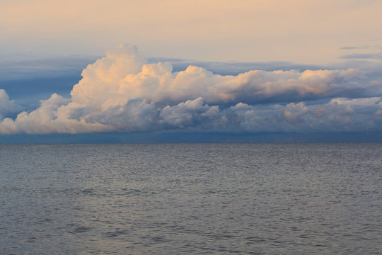 Low dramatic fluffy clouds over sea water