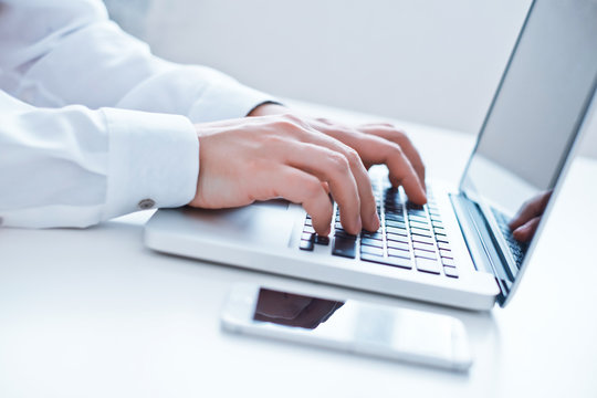 Businessman using laptop at the office. Close-up image.