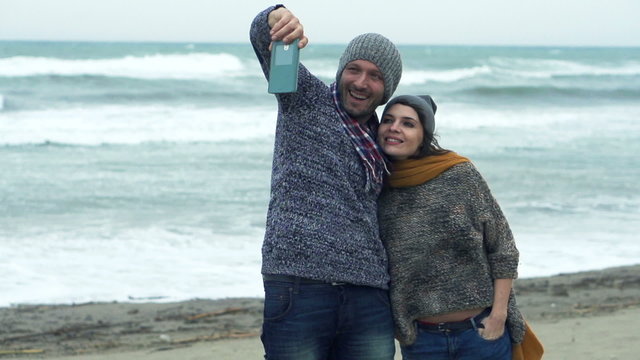 Young couple taking selfie photo on beach on a stormy day, super slow motion
