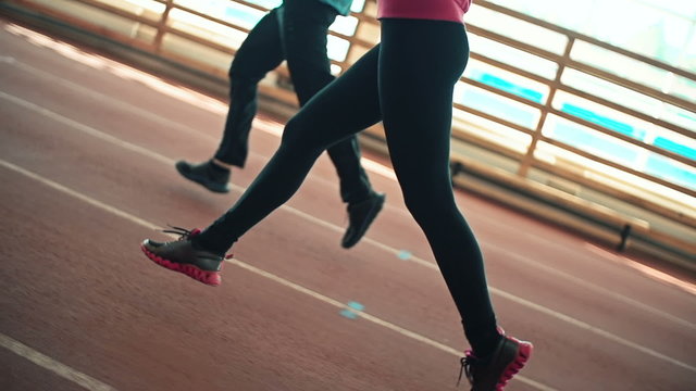 Legs of two runners jogging in stadium together