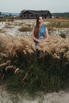 cute countryside lady standing in tall grass against ranch house
