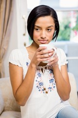 Thoughtful brunette holding white cup
