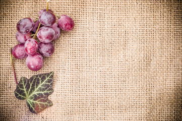 Grapes on a burlap sackcloth with ivy leaf. Background with copy-space