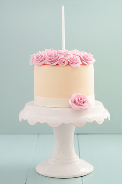 Ivory fondant covered cake with pink sugar roses on cake stand