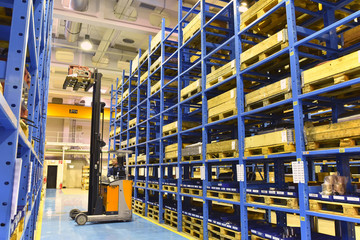 Hochregallagerung im Gewerbe - Gabelstapler entnimmt Waren aus dem Regal // High bay warehouse with forklift