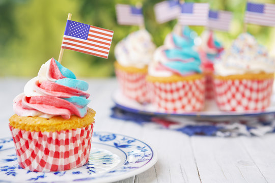Cupcakes with red-white-and-blue frosting and American flags on