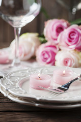 Pink candle and roses on the table