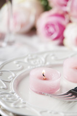 Pink candle and roses on the table