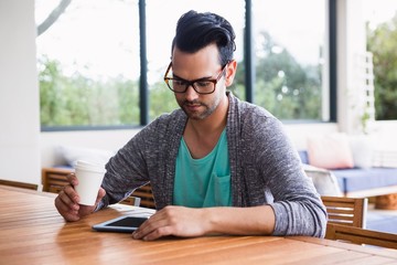 Designer with take-away coffee using tablet 