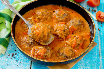 Homemade meatballs in tomato sauce with spices in a rustic style