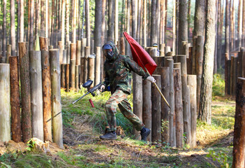 Running boy with paintball gun and red flag
