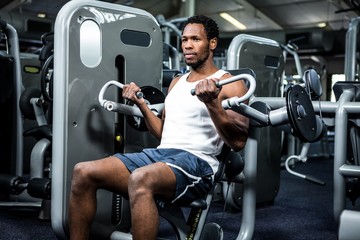 Fototapeta na wymiar Serious muscular man using exercise machine 