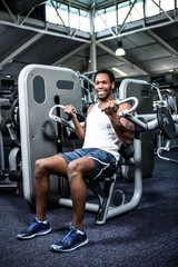 Fototapeta na wymiar Smiling muscular man using exercise machine 