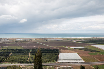 view of landscape with the sea, fiedls and clouds