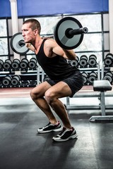 Obraz na płótnie Canvas Muscular man exercising with barebell