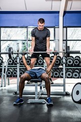 Fototapeta na wymiar Trainer helping muscular man lifting barebell 