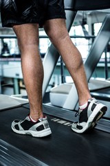Naklejka na ściany i meble Cropped image of muscular man using treadmill