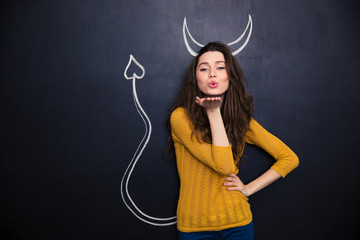 Cute woman with devils horns and tail drawn on blackboard