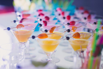 Beautiful row line of different colored alcohol cocktails with mint on a christmas party, martini, vodka,and others on decorated catering bouquet table on open air event, picture with beautiful bokeh