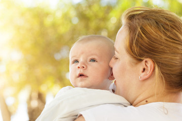 Portrait of loving mother hugging her baby outdoors