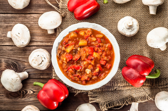 Letcho with paprika and mushrooms on wood. 