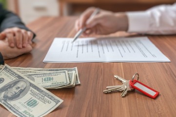 Real estate concept. Realtor agent offering the contract to sign. Money and keys on desk. - obrazy, fototapety, plakaty