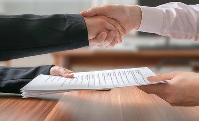 Partnership concept. Business man and woman shaking hands and passing contract. - obrazy, fototapety, plakaty