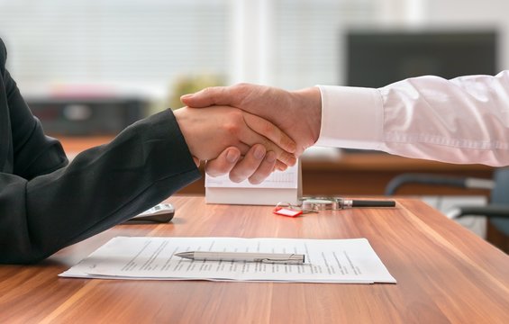 Partnership concept. Businessman and woman sitting behind desk with agreement.