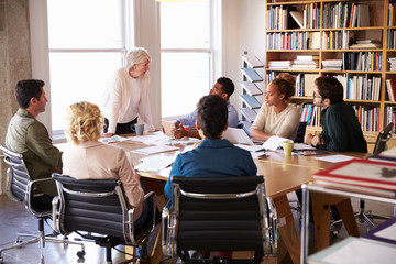 Senior Businesswoman Addressing Team Meeting Around Table