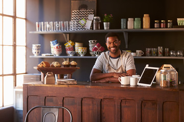 Portrait Of Male Coffee Shop Owner Standing Behind Counter