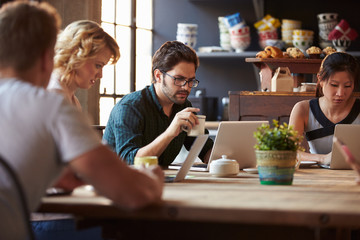 Interior Of Coffee Shop With Customers Using Digital Devices
